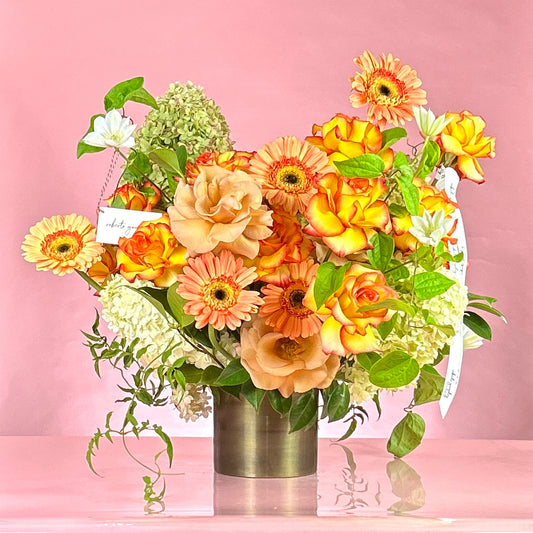 Bouquet of flowers in a clear vase against a pink background