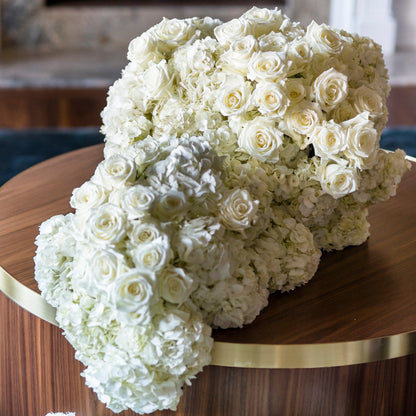 Large bouquet of white flowers on a wooden table in an indoor setting